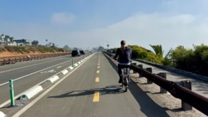 Cyclist rides southbound on the Highway 101 cycle track or separated bikeway in Encinitas, California