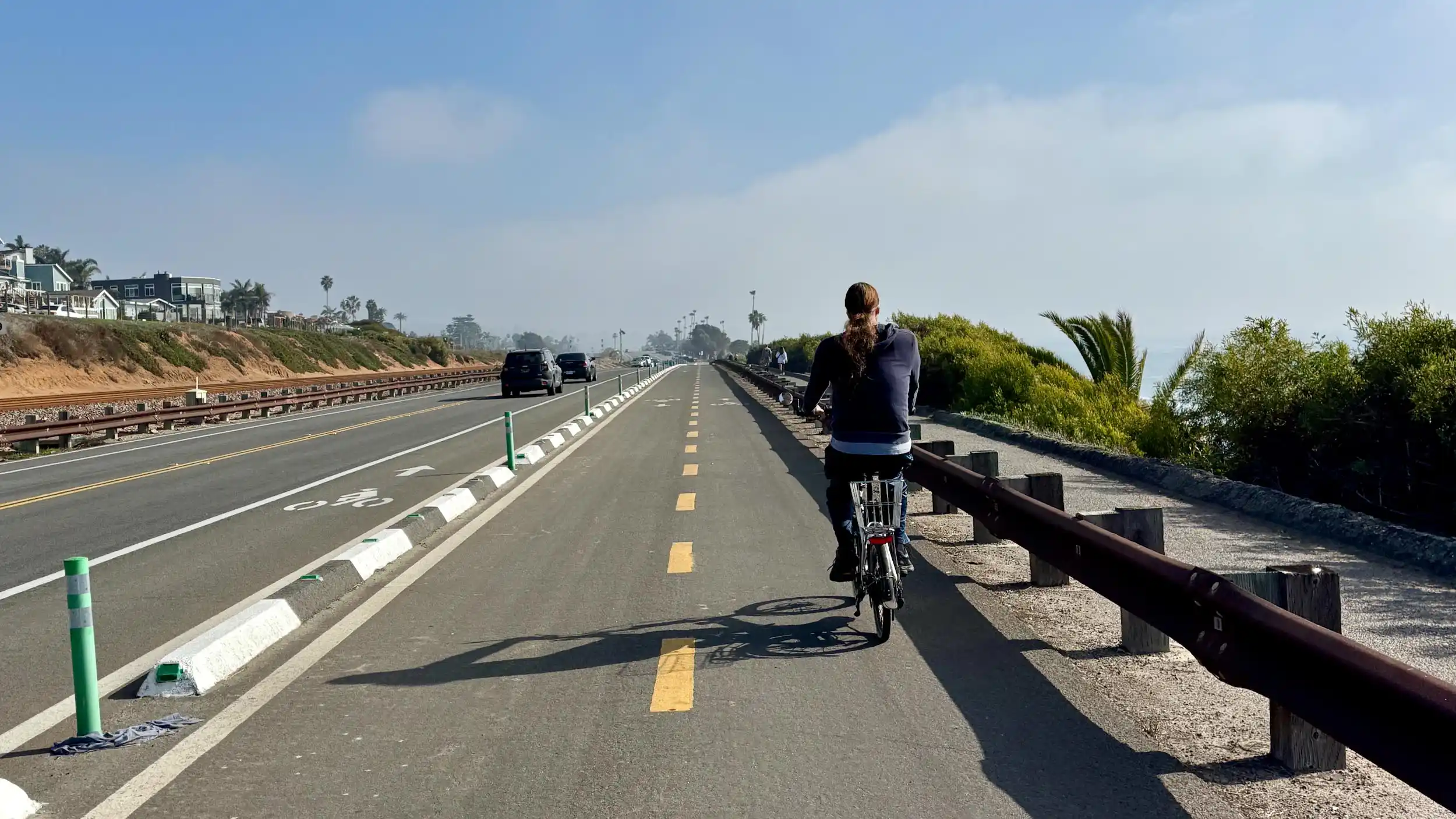 Cyclist rides southbound on the Highway 101 cycle track or separated bikeway in Encinitas, California