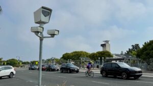 A red-light camera in Solana Beach, California with cars and a cyclist in the background